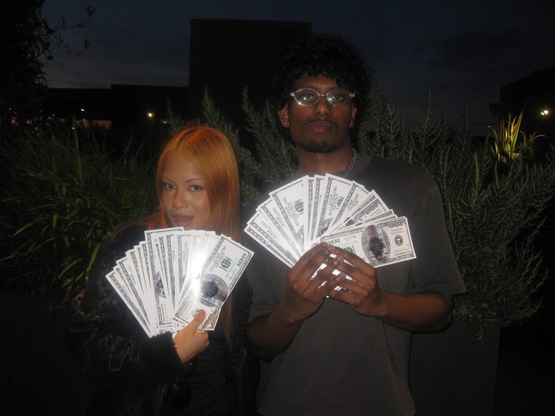 Two people at night each fanning out a large stack of Mahdi Bucks notes